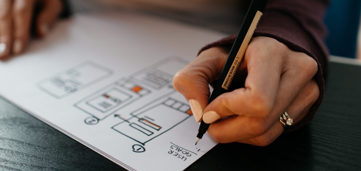 designer drafting mobile wireframes, flows, and user goals on paper