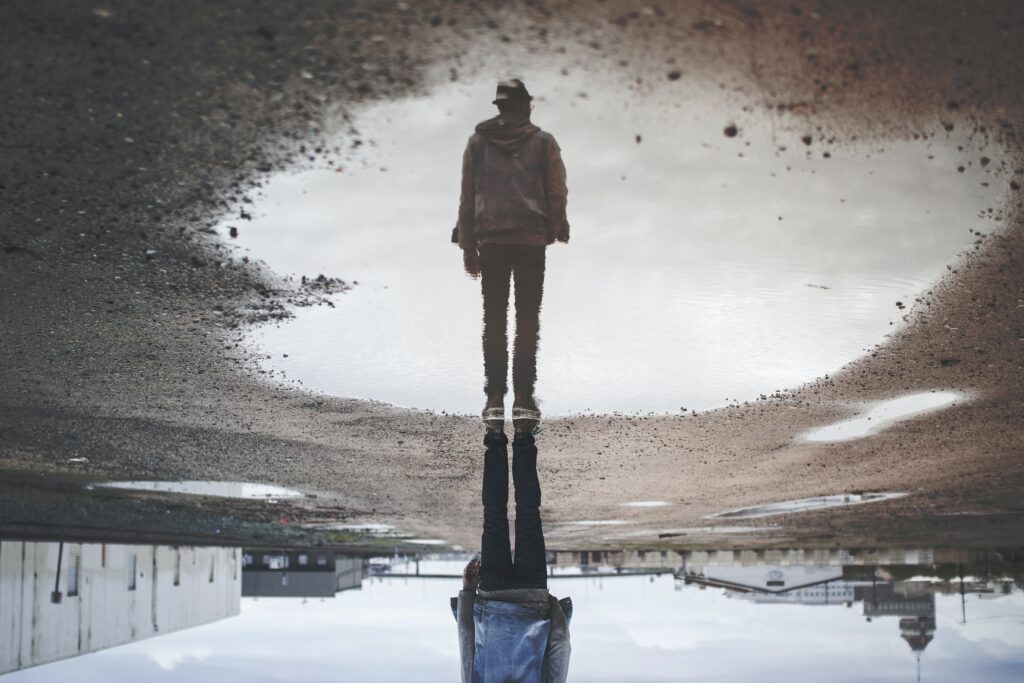 inverted image of man near puddle whose reflection is right side up