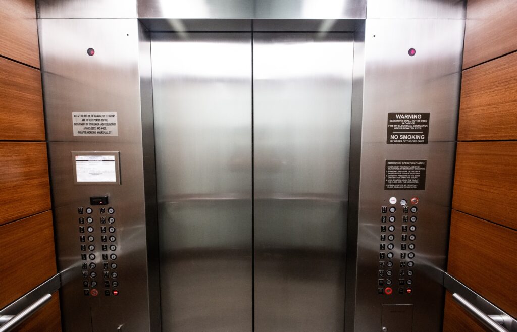 Stainless steel elevator door with buttons, symbolizing the intricacies of systems and the necessity of rigorous testing.