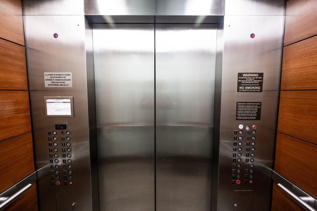 Stainless steel elevator door with buttons, symbolizing the intricacies of systems and the necessity of rigorous testing.